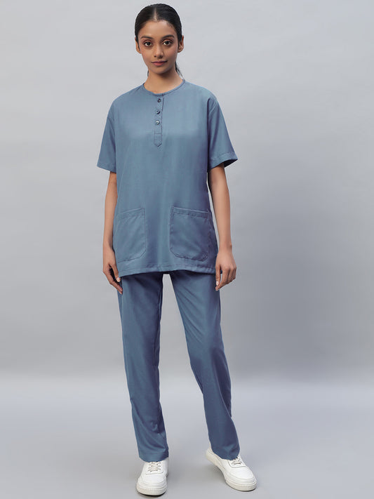 Teal coloured Medical Scrub Suit Set with a round neck and 3 buttons, half sleeves, with a front pocket, and matching pants . 